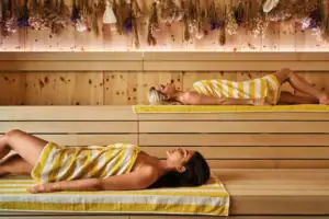 A woman is lying on a bench in a sauna.
