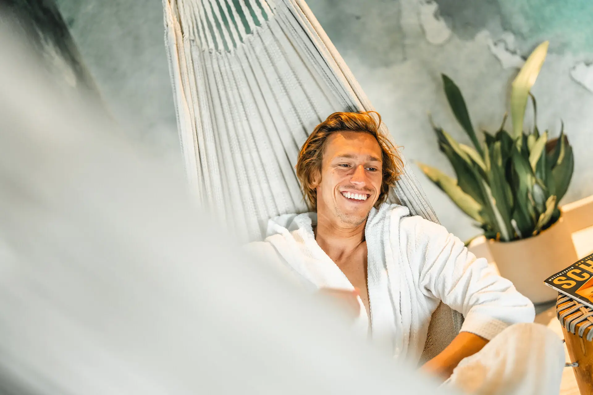 Day Spa Urban Nature St. Peter-Ording A man in a bathrobe lies smiling in a hammock at the Urban Nature Hotel.