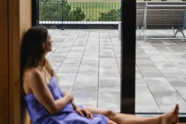 Sauna Eine Frau sitzt auf einer Fensterbank und schaut aus dem Fenster.