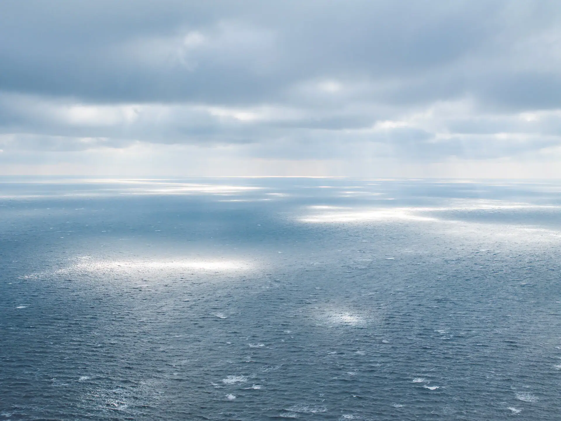 Sea Winter A large body of water with rays of sunlight shining through the clouds.