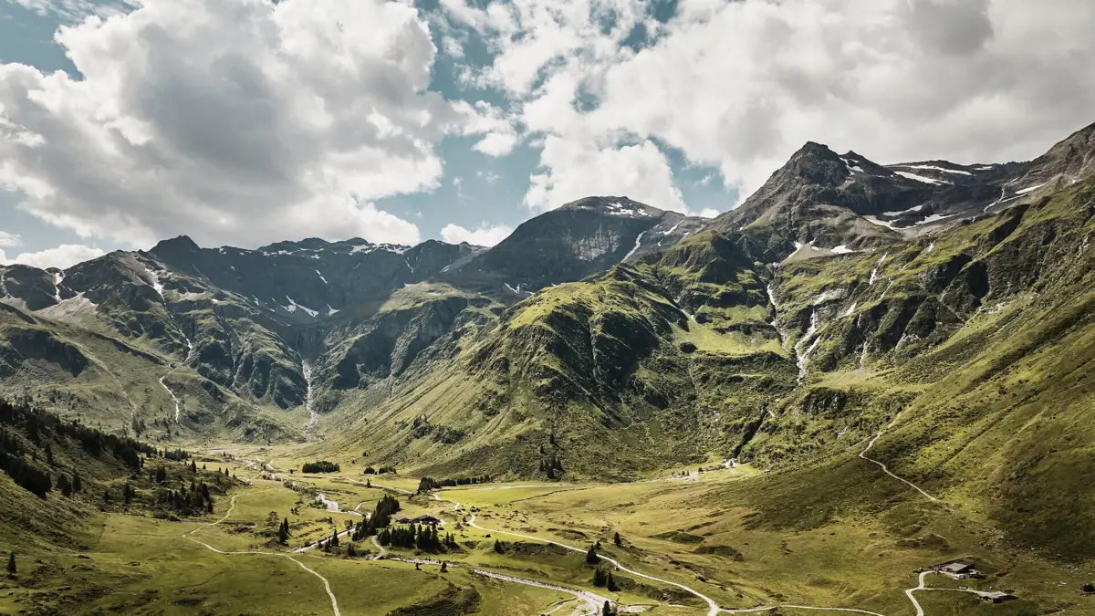 A winding road through a valley, with mountains in the background.