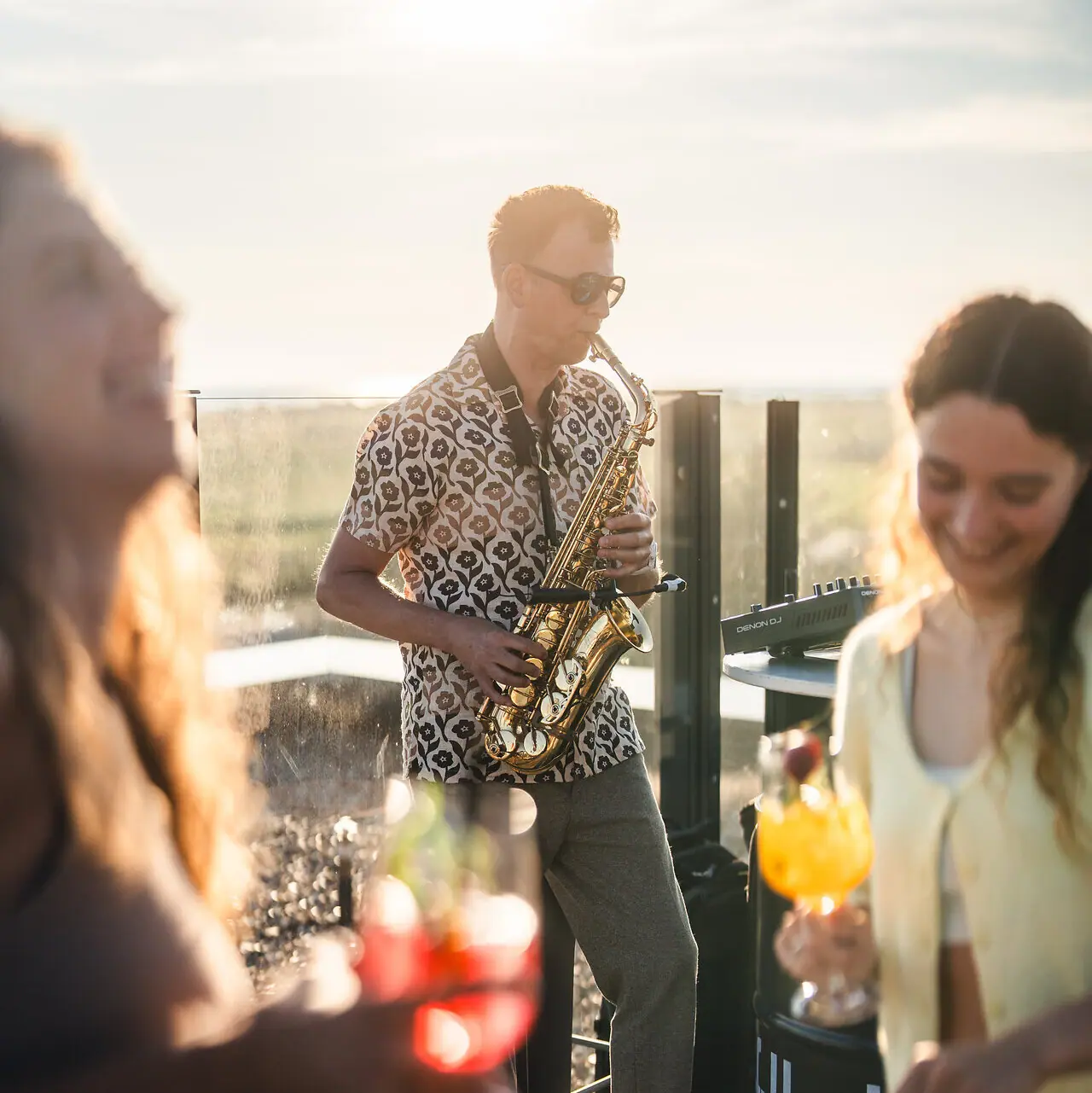 A man is playing the saxophone whilst a woman is dancing.